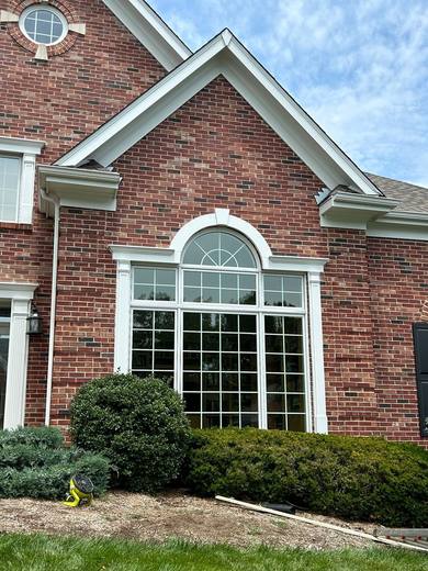 Large arched window with grilles below a brick gable