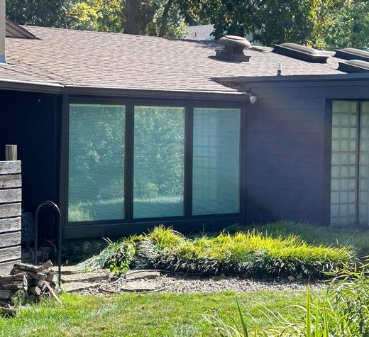 Black-framed picture windows on a home with dark siding