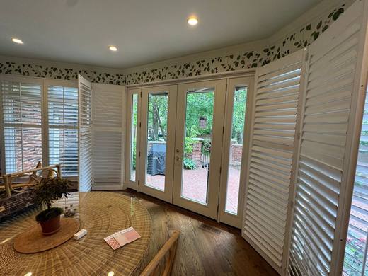 French patio door with sidelights, framed by white plantation shutters